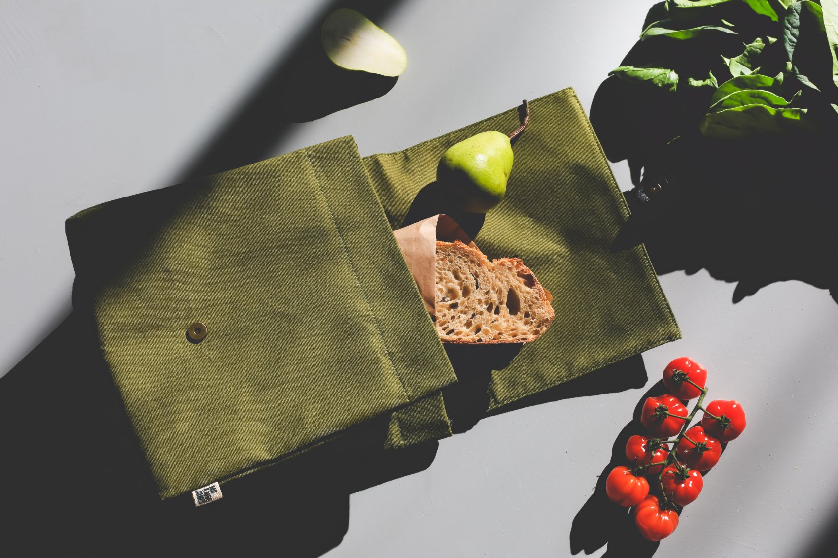 Green canvas lunch bag with bread and produce